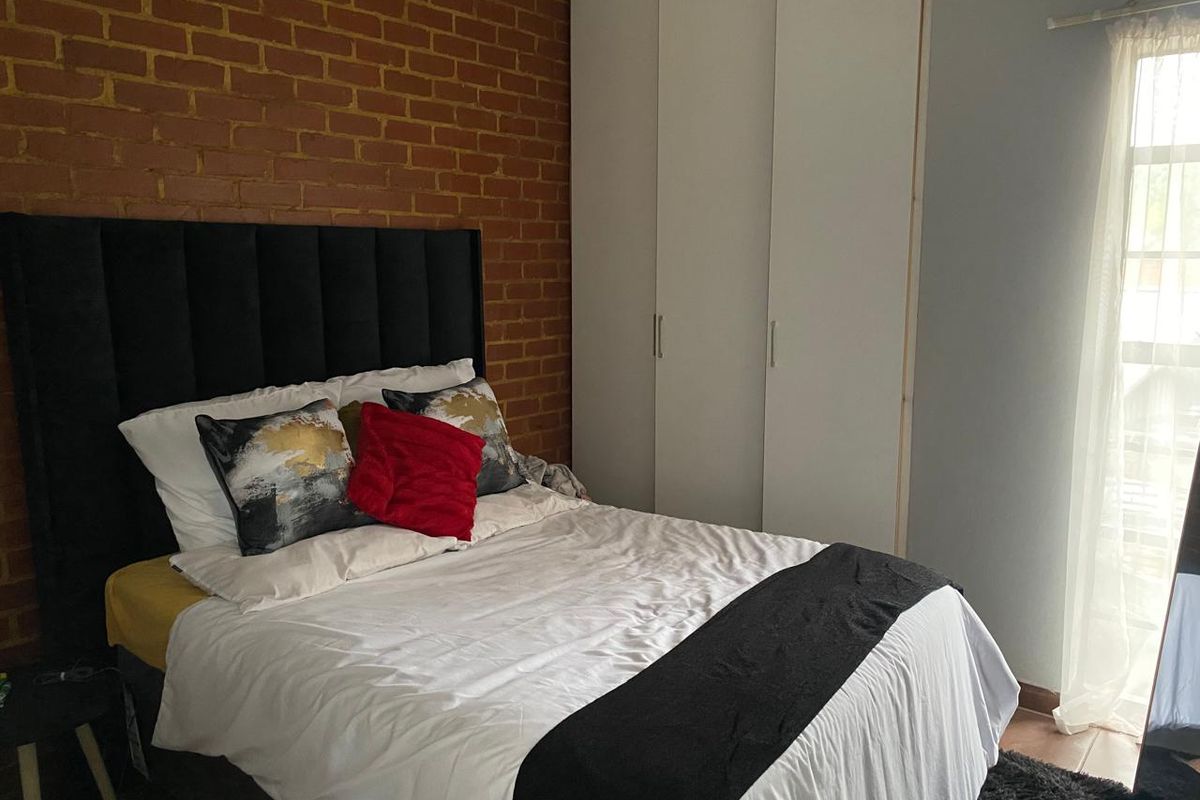 A bedroom featuring a rustic exposed brick feature wall and built-in white cabinetry, providing ample storage space.