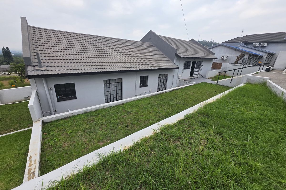 A view of the rear exterior of the house, featuring a terraced garden with retaining walls and a tiled roof structure.