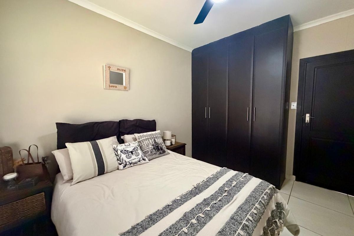 A well-maintained bedroom featuring built-in dark wood cabinetry, tiled flooring, and a ceiling fan.