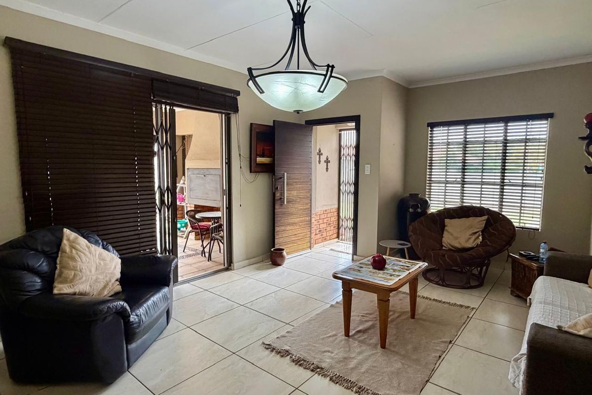 Spacious living room featuring large ceramic floor tiles, a decorative pendant light fixture, and direct access to an outdoor patio area.