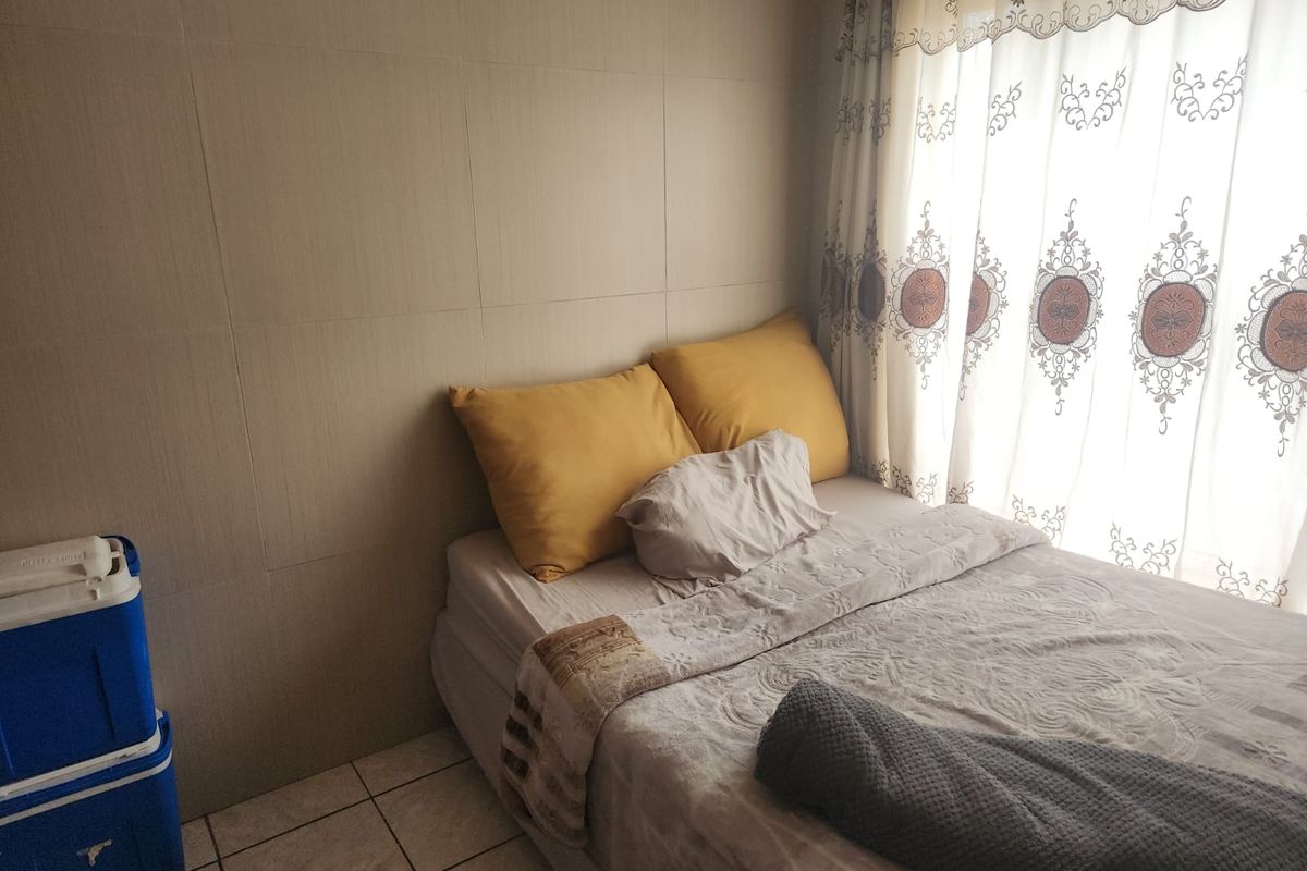 A bedroom featuring tiled flooring and neutral wall finishes, providing a functional space for rest.