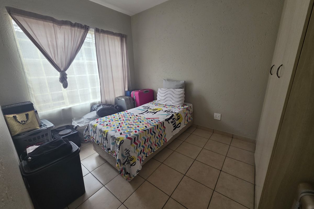 A functional bedroom featuring tiled flooring and a built-in wardrobe, offering a practical living space with natural light.