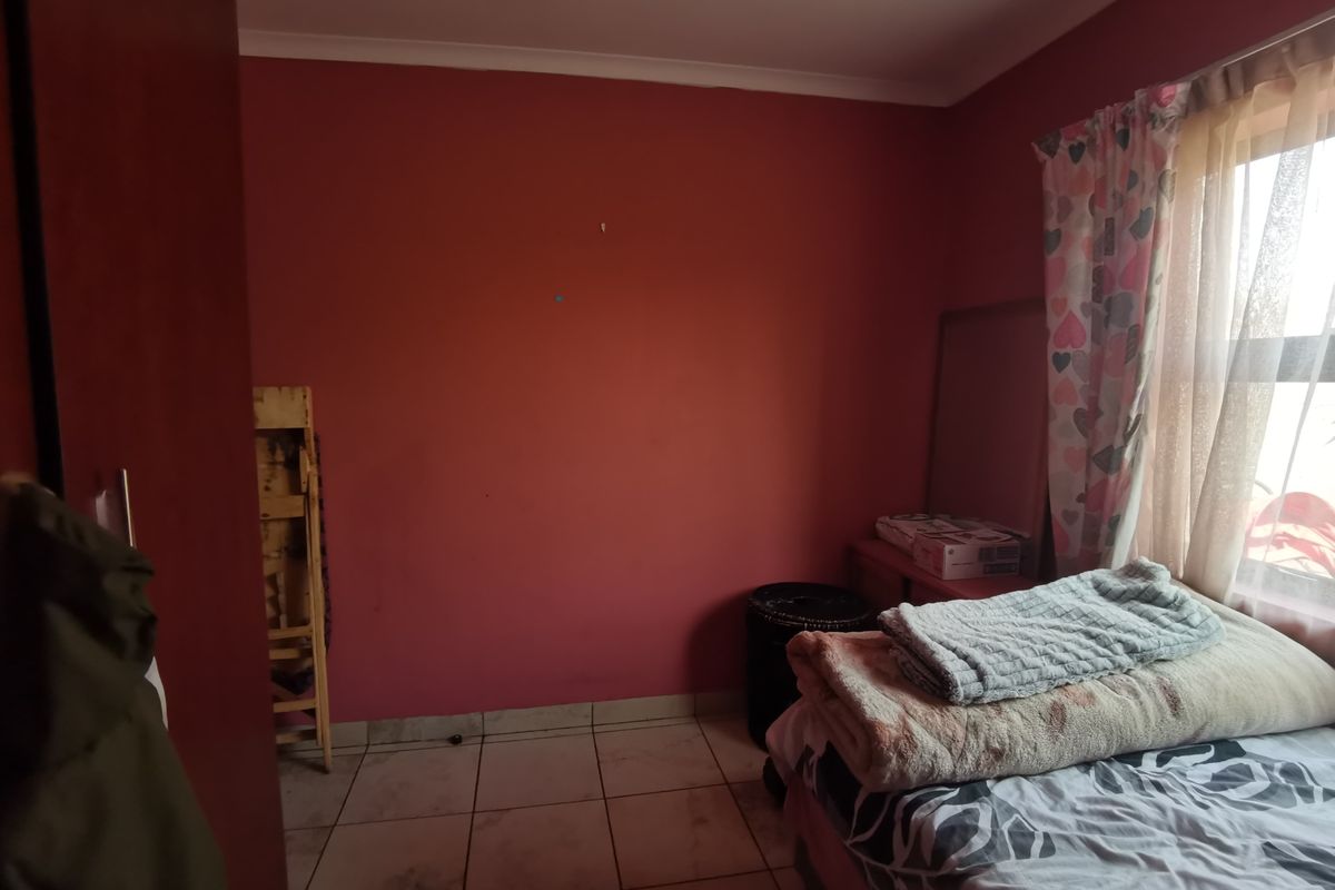 A bedroom featuring tiled flooring and a built-in cupboard, currently requiring cosmetic updates to the wall finishes and flooring.