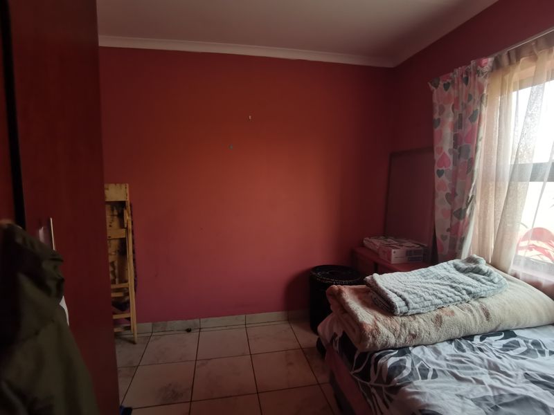 A bedroom featuring tiled flooring and a built-in cupboard, currently requiring cosmetic updates to the wall finishes and flooring.