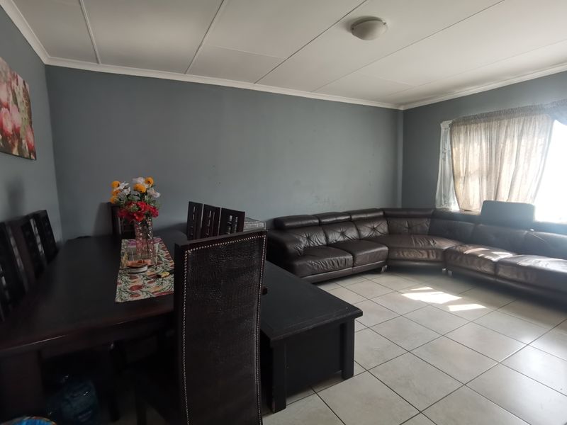 Open plan living and dining area featuring tiled flooring and neutral grey walls, providing a functional space for family gatherings.