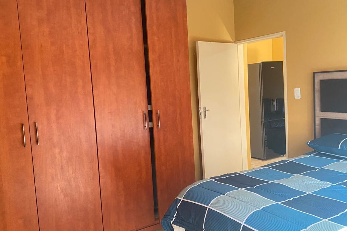 A bedroom featuring built-in wooden cupboards and a doorway leading to an adjacent room.