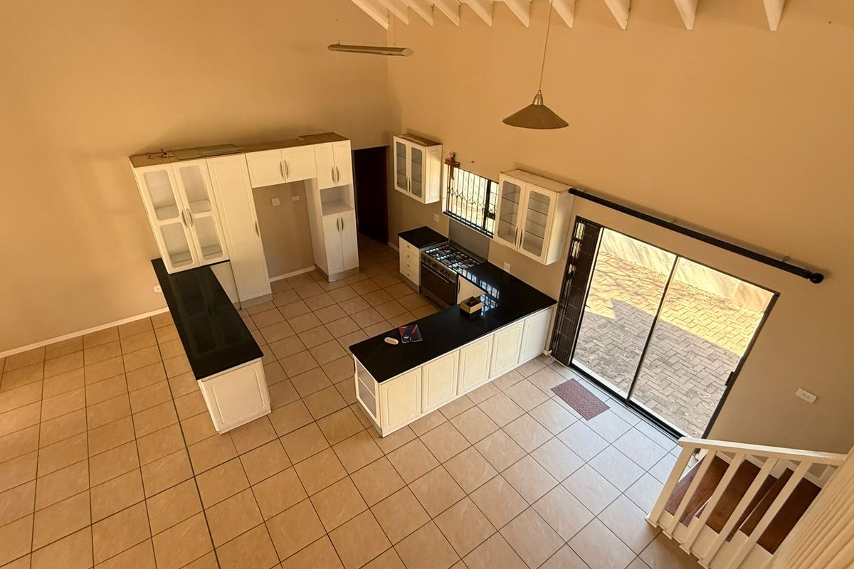Spacious kitchen featuring white cabinetry, granite countertops, gas stove, and vaulted ceilings, with direct access to the outdoor patio area.
