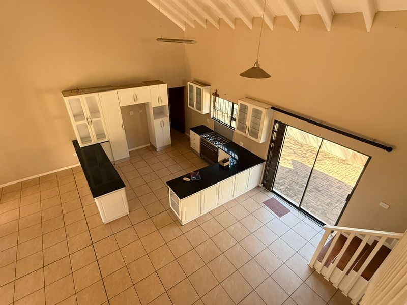 Spacious kitchen featuring white cabinetry, granite countertops, gas stove, and vaulted ceilings, with direct access to the outdoor patio area.