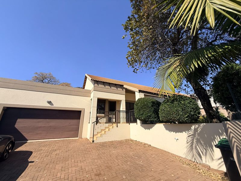 Front elevation of the property featuring a paved driveway, double garage, and an elevated entrance with a tiled roof.