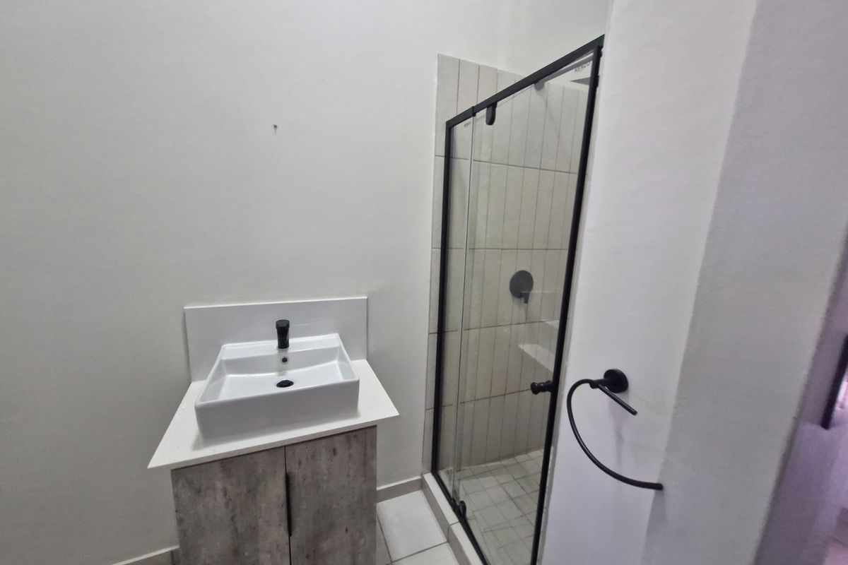 Modern bathroom featuring a contemporary vanity with a vessel sink and a glass-enclosed shower with tiled finishes.