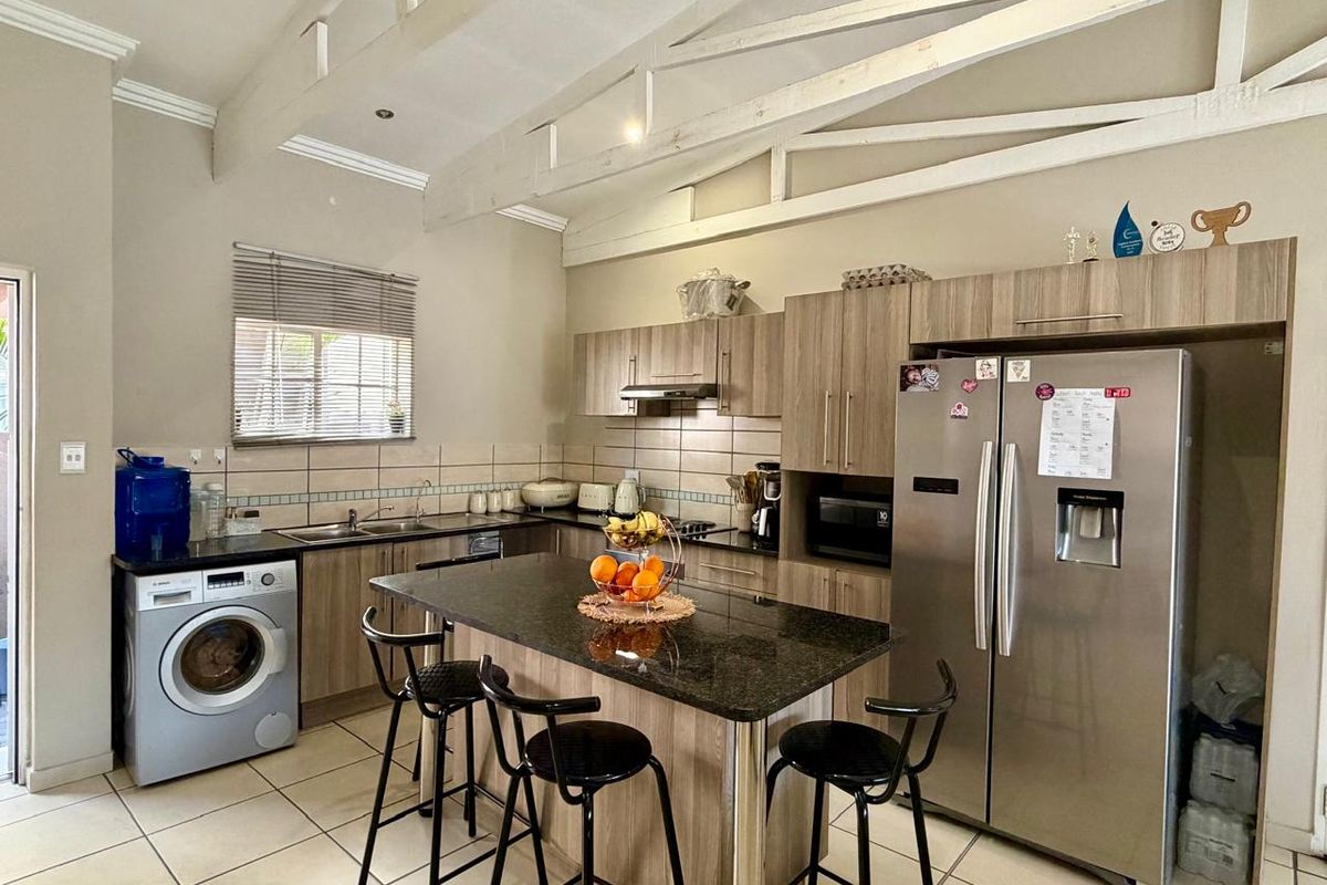A functional kitchen featuring granite countertops, a central island, built-in cabinetry, and exposed roof trusses, providing a spacious and practical cooking area.