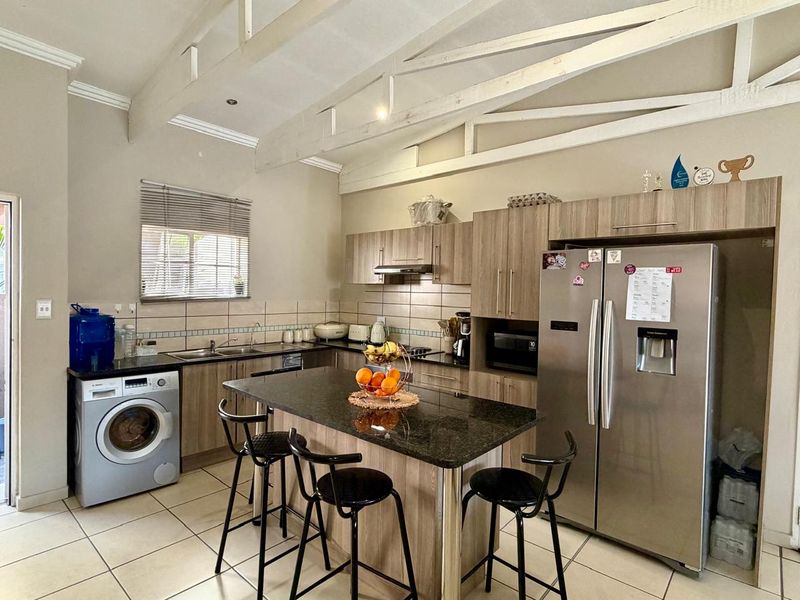 A functional kitchen featuring granite countertops, a central island, built-in cabinetry, and exposed roof trusses, providing a spacious and practical cooking area.