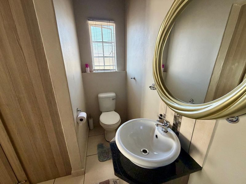 A compact guest bathroom featuring a modern vessel basin on a vanity, a toilet, and a window with venetian blinds.