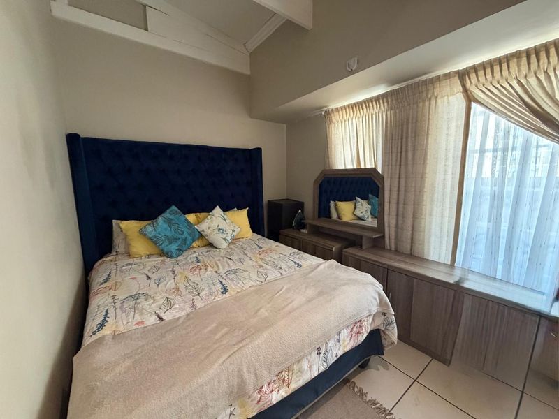 A bedroom featuring built-in cabinetry, tiled flooring, and a vaulted ceiling with visible ceiling panel damage.