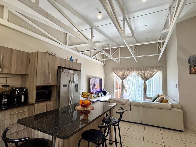 Spacious open-plan living area featuring exposed timber roof trusses, a modern kitchen with granite island, and seamless flow to the living space.