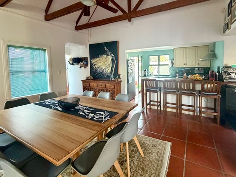Open-plan dining and kitchen area featuring exposed timber roof trusses, terracotta flooring, and a functional breakfast bar with integrated cabinetry.
