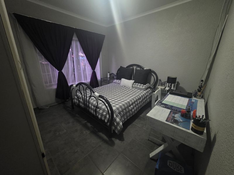 A standard bedroom featuring tiled flooring and neutral wall finishes, providing a functional space for rest.