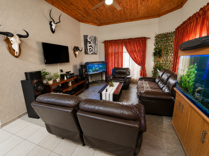A living room featuring a vaulted timber ceiling, ceiling fan, and tiled flooring, providing a comfortable space for relaxation and entertainment.