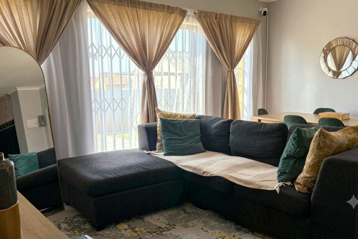 A well-lit living area featuring a security gate on the window and a mounted security camera, providing a comfortable and secure living space.