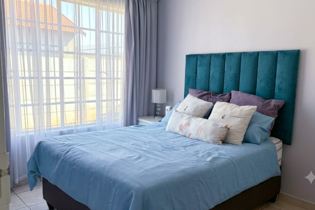 A well-lit bedroom featuring tiled flooring and a large window, providing a bright and comfortable living space.
