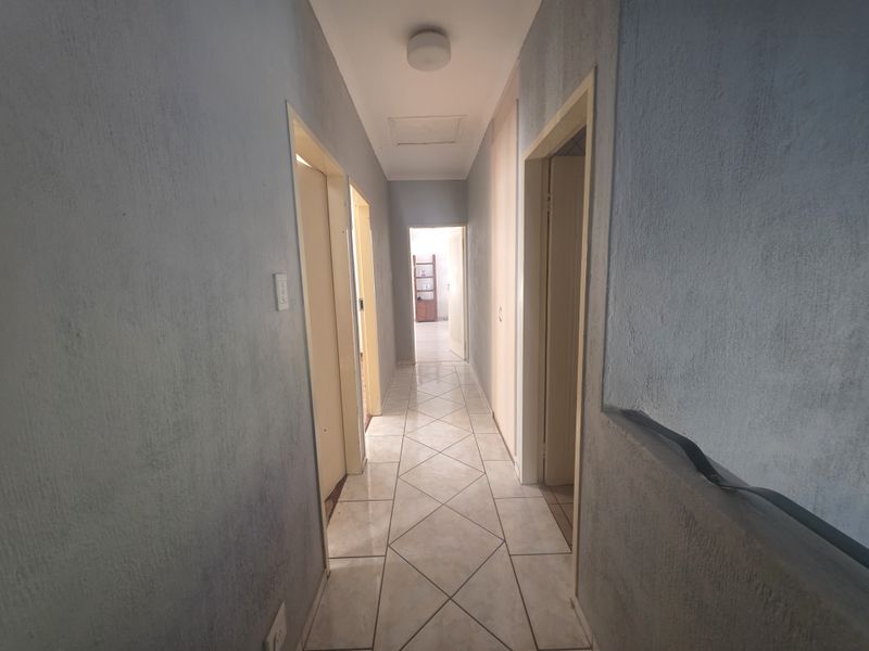 A functional hallway featuring tiled flooring and multiple doorways leading to adjacent rooms, with neutral wall finishes.