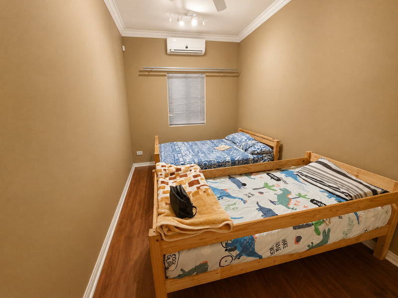 A bedroom featuring laminate flooring, crown molding, a wall-mounted split-system air conditioner, and venetian blinds.