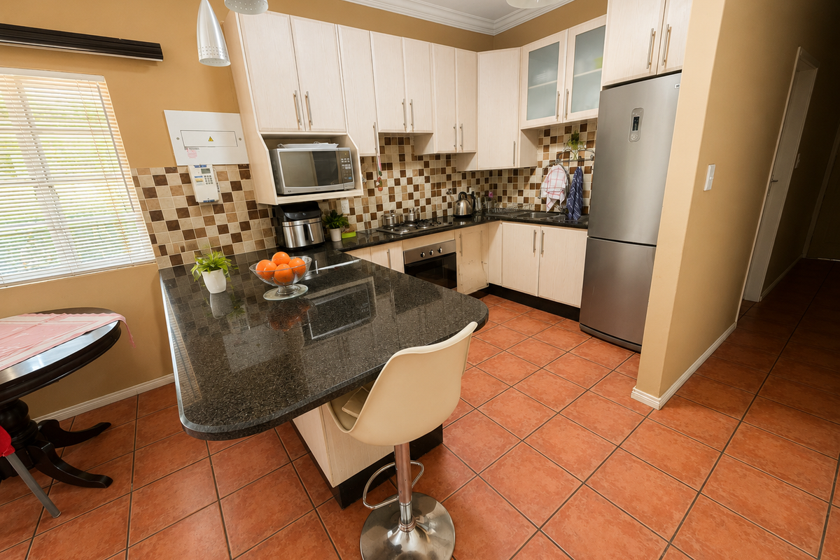 A functional kitchen featuring granite countertops, built-in oven, gas hob, and light-toned cabinetry with a tiled backsplash and ceramic flooring.