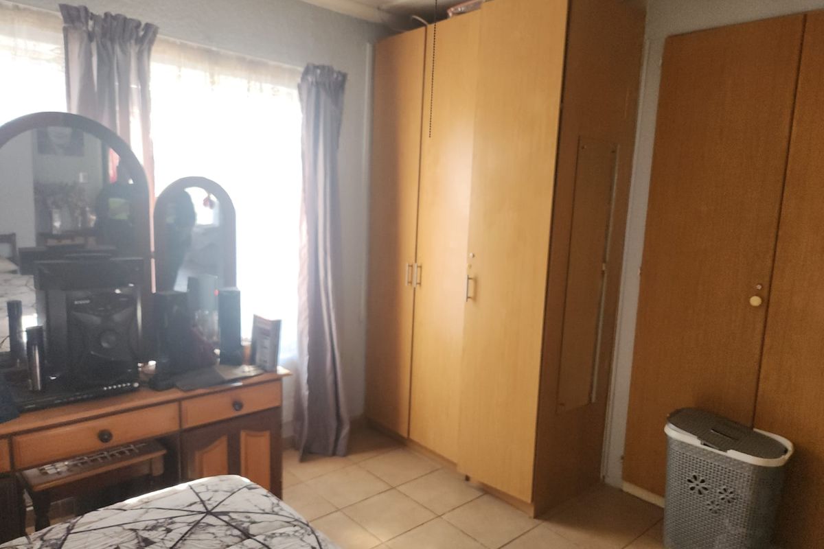 A bedroom featuring built-in wooden cupboards and tiled flooring, offering functional storage space.