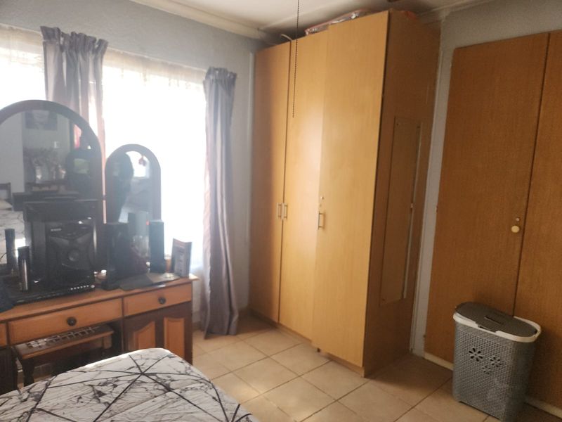A bedroom featuring built-in wooden cupboards and tiled flooring, offering functional storage space.