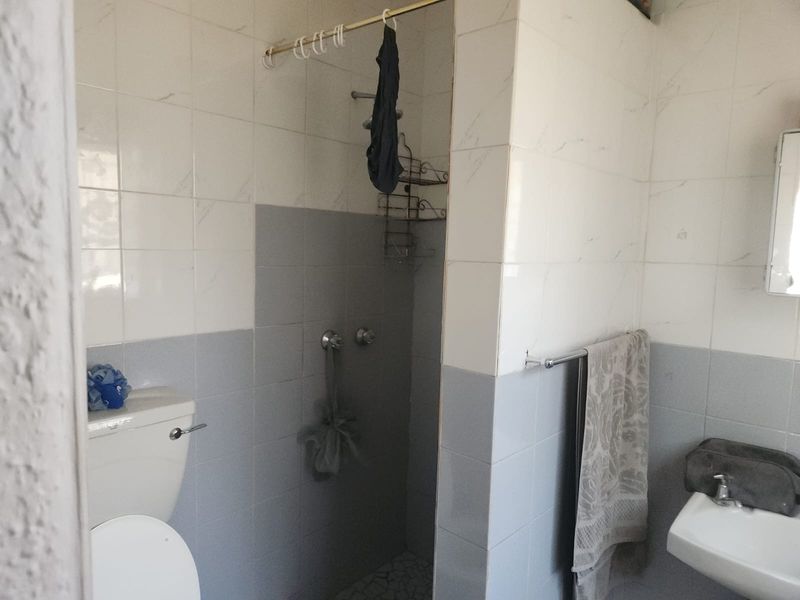 A functional bathroom featuring a shower, toilet, and washbasin with two-tone wall tiling.