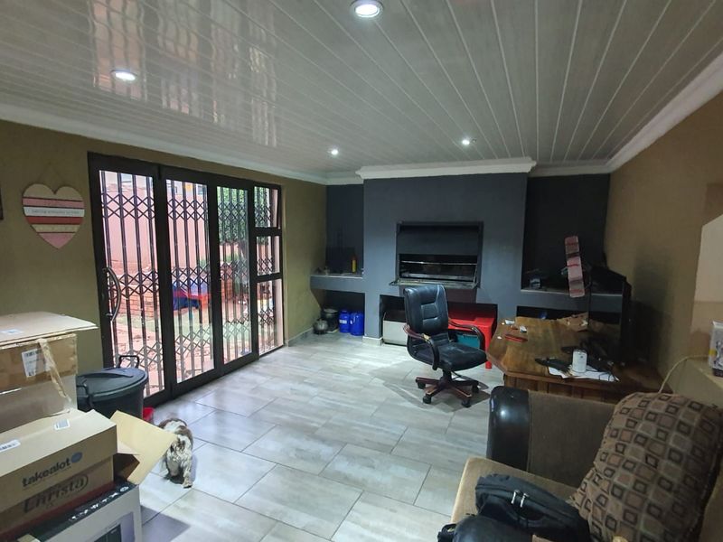 Enclosed patio area featuring a built-in braai, tiled flooring, and recessed lighting, providing a versatile space for indoor-outdoor entertaining.