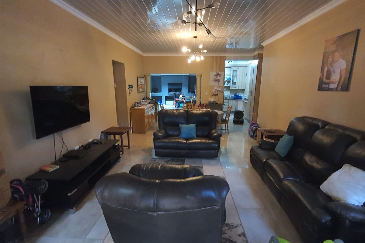 Open-plan living area featuring tiled flooring and a glossy ceiling finish, flowing into the kitchen space.