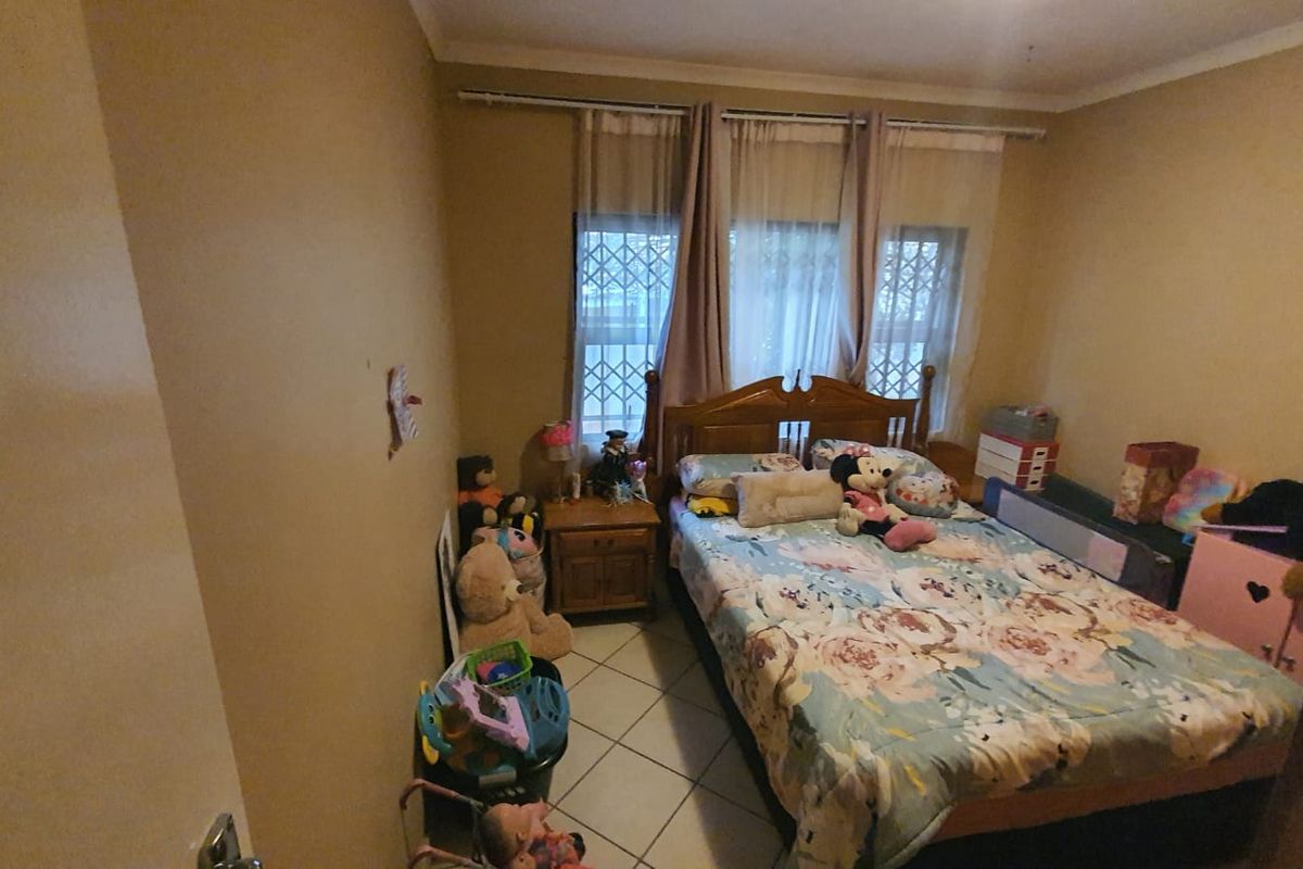 A bedroom featuring tiled flooring and security burglar bars on the windows, providing a functional space with potential for cosmetic updates.