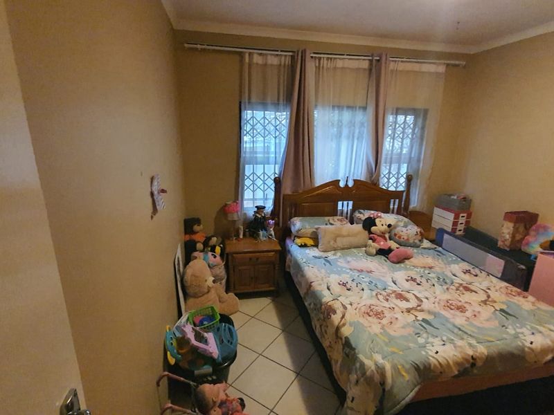 A bedroom featuring tiled flooring and security burglar bars on the windows, providing a functional space with potential for cosmetic updates.