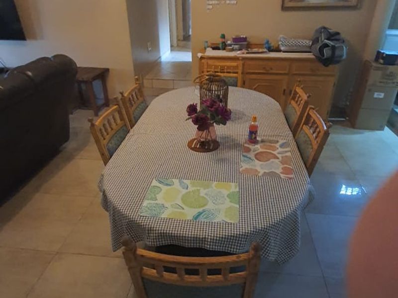 A dining area featuring neutral wall tones and large format floor tiles, providing a functional space for family meals.