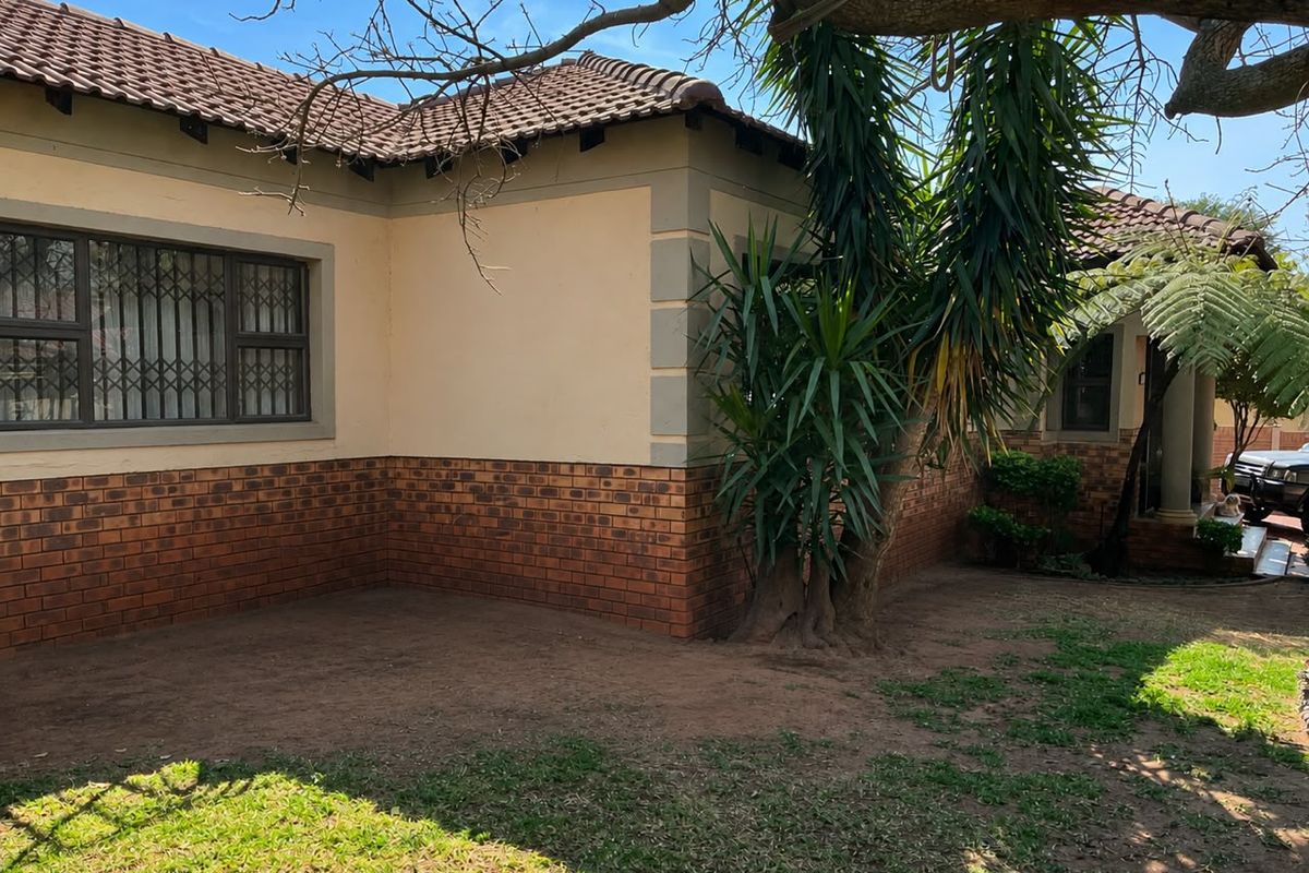 Rear exterior view of the townhouse featuring a brick and plaster facade, tiled roof, and security-fitted windows overlooking a garden area.
