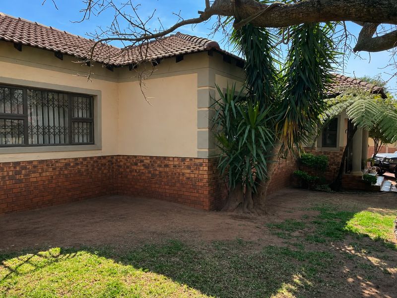 Rear exterior view of the townhouse featuring a brick and plaster facade, tiled roof, and security-fitted windows overlooking a garden area.