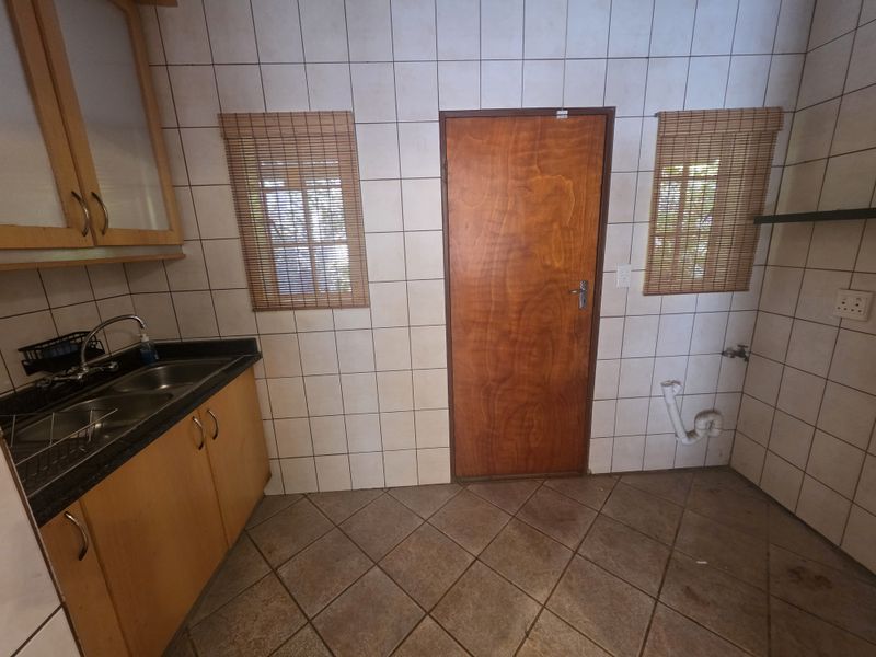 A functional laundry area featuring tiled walls and flooring, a double sink with cabinetry, and dedicated plumbing connections for appliances.