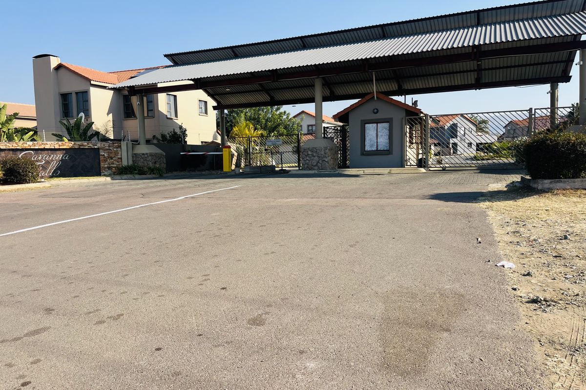 The entrance to the residential estate features a secure guard house, metal roof canopy, and gated access point.