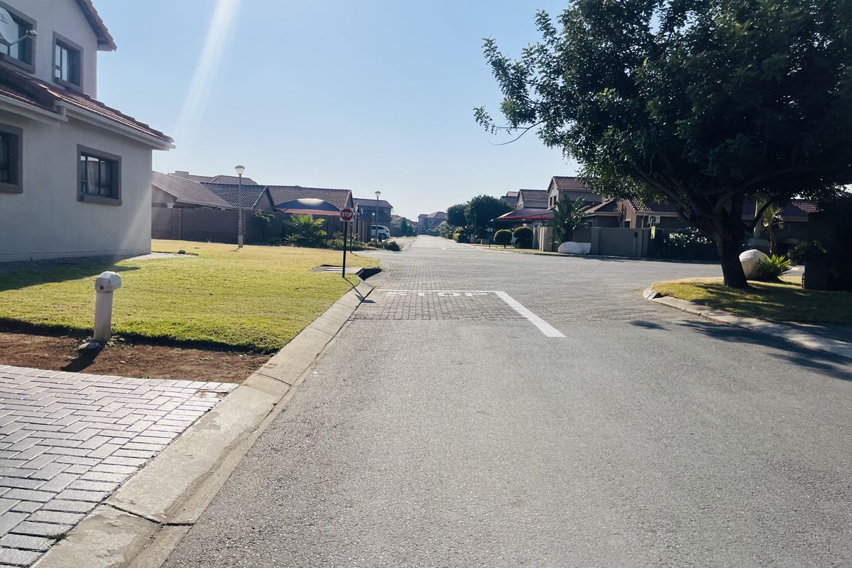 A clear street view of a well-maintained residential estate featuring paved roads, neat verges, and established suburban housing.