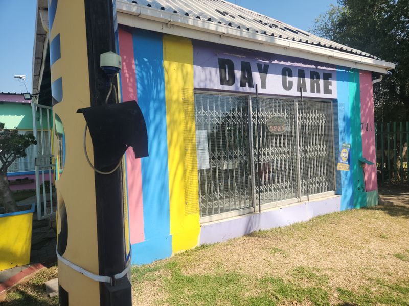 Front exterior view of a commercial property featuring a metal roof, security gates, and painted facade.