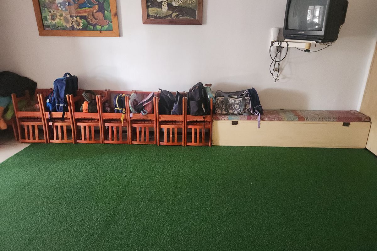A living area featuring a built-in storage bench and green carpeting, currently used as a multi-purpose space.