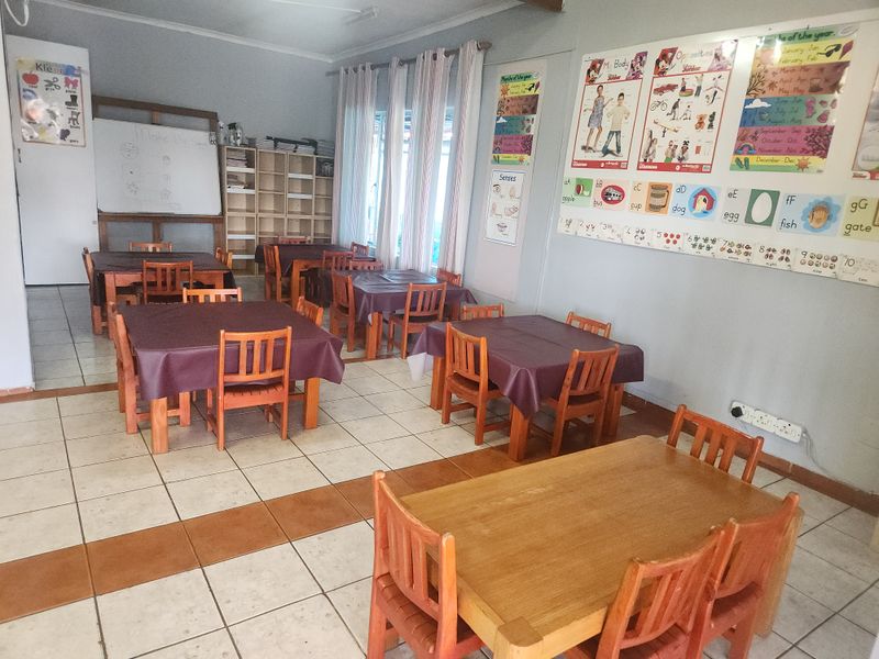 A multi-purpose room currently utilized as a classroom, featuring ceramic tile flooring and built-in shelving units.