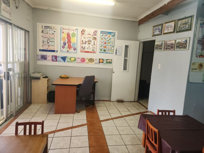 A multi-purpose room featuring tiled flooring and a sliding glass door, currently utilized as a learning or office space.