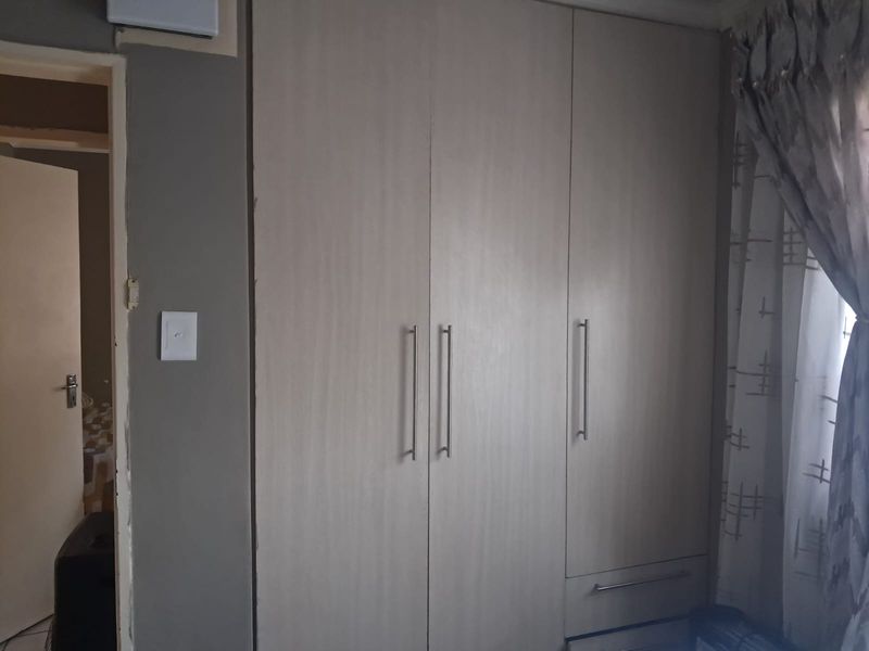 Bedroom featuring built-in cupboards with modern handles and neutral finishes, providing ample storage space.