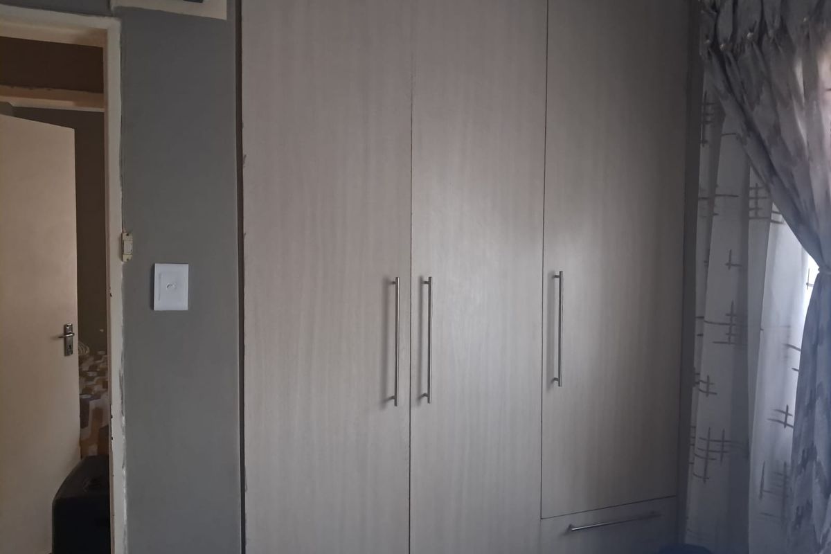 Bedroom featuring built-in cupboards with modern handles and neutral finishes, providing ample storage space.