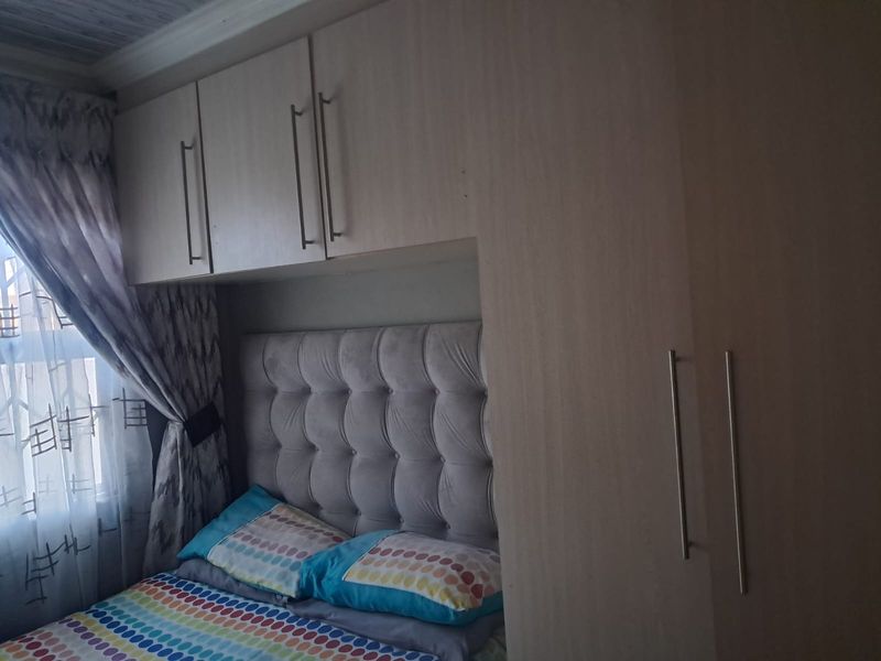 A bedroom featuring built-in cupboards and overhead storage cabinets, providing efficient storage solutions around the bed area.