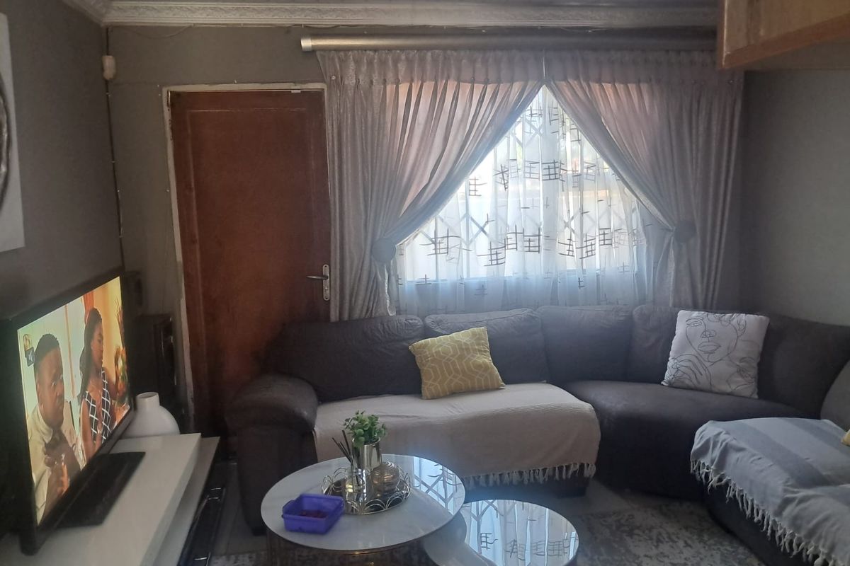 A cozy living room featuring tiled flooring, decorative cornice, and a security gate leading to an exterior door.