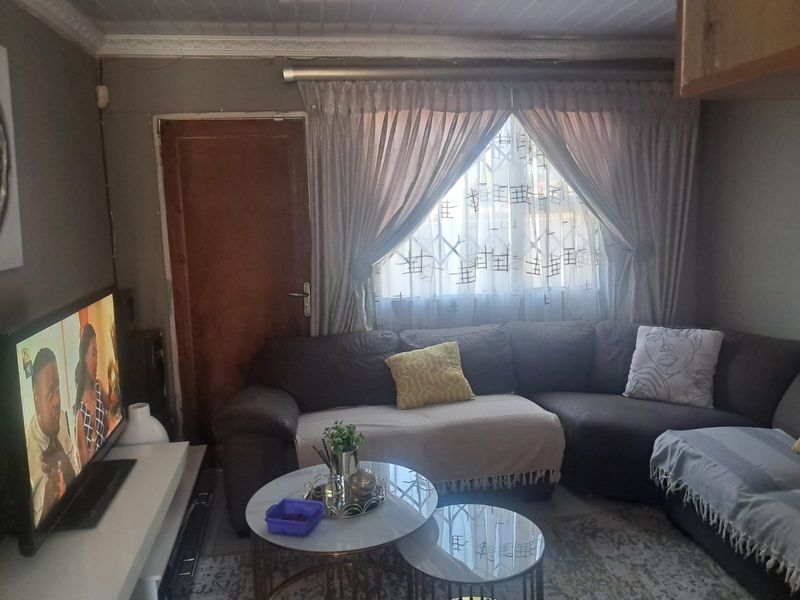 A cozy living room featuring tiled flooring, decorative cornice, and a security gate leading to an exterior door.