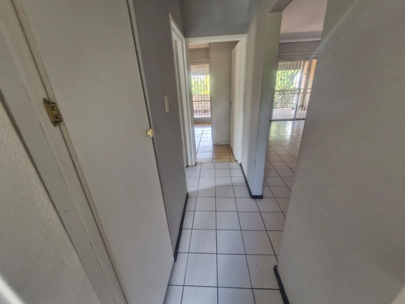 A functional hallway featuring tiled flooring and built-in storage, providing access to adjacent living areas and a balcony with security gates.